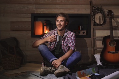 Photo of Handsome young traveler with mug indoors