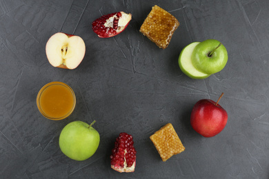 Photo of Flat lay composition with honey and fruits on grey table, space for text. Rosh Hashanah holiday