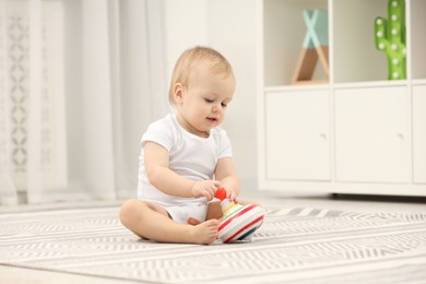 Children toys. Cute little boy playing with spinning top on rug at home