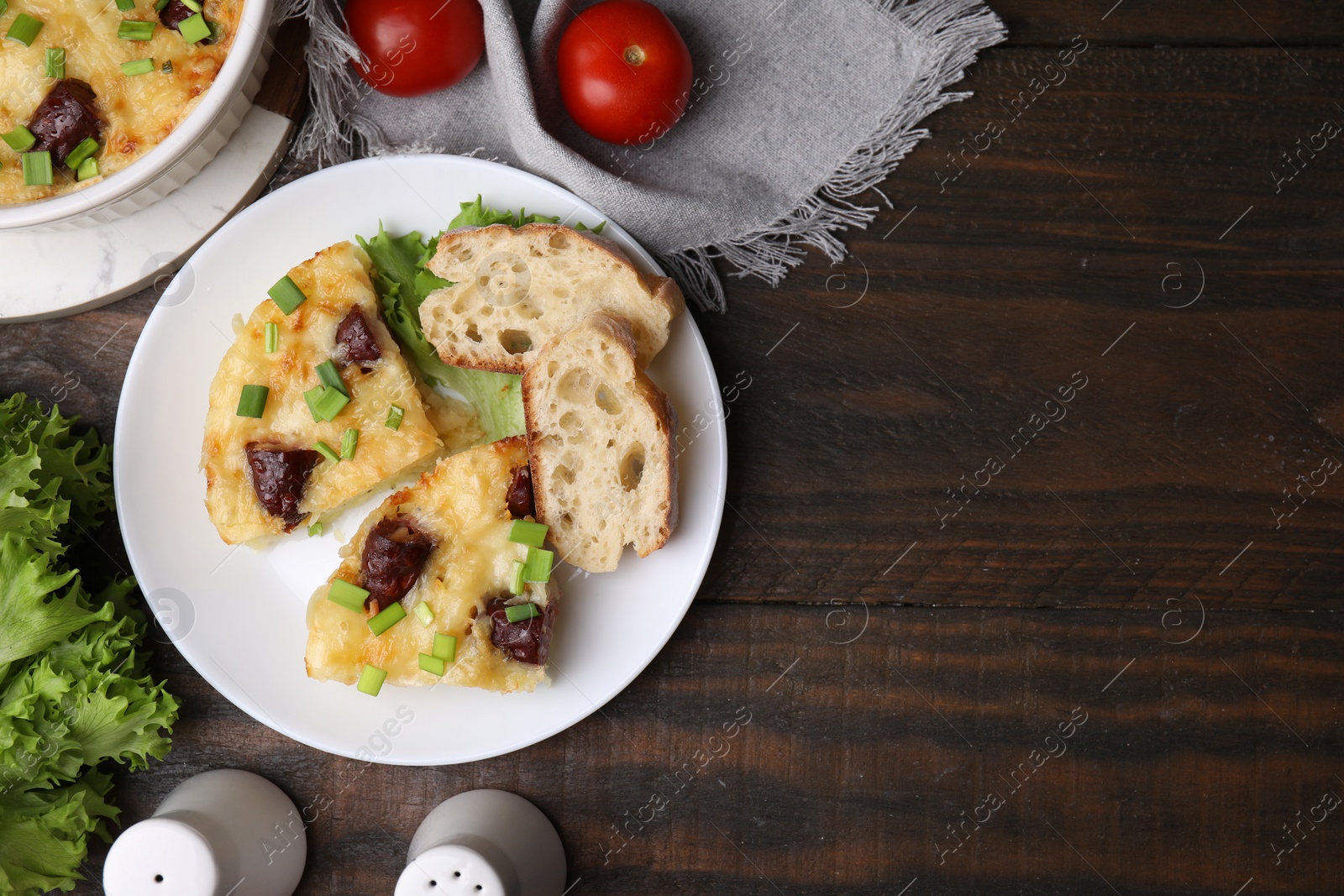 Photo of Tasty sausage casserole with green onion served on wooden table, flat lay. Space for text