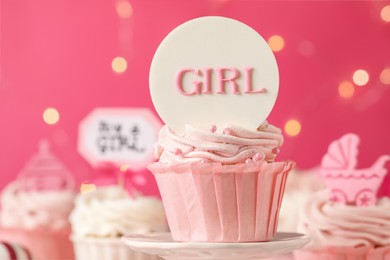 Beautifully decorated baby shower cupcake for girl with cream and topper on pink background