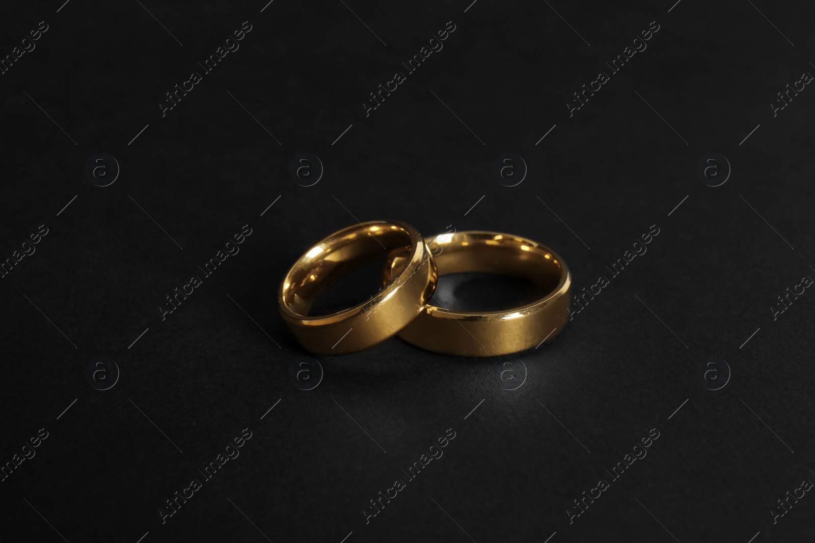 Photo of Elegant gold wedding rings on black background