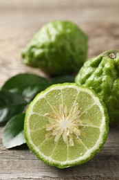 Fresh ripe bergamot fruits with green leaves on wooden table, closeup