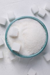 Different types of sugar in bowl on white table, flat lay