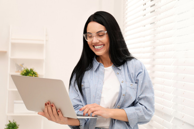 Photo of Beautiful young woman working with laptop indoors