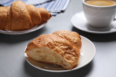 Tasty fresh croissant on light grey table, closeup