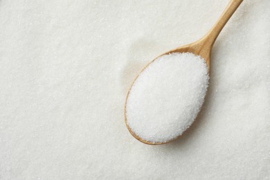 Photo of Wooden spoon on granulated sugar, top view
