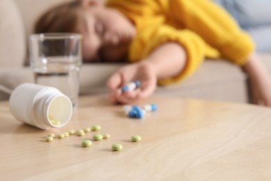 Different pills and unconscious little child on background. Danger of medicament intoxication