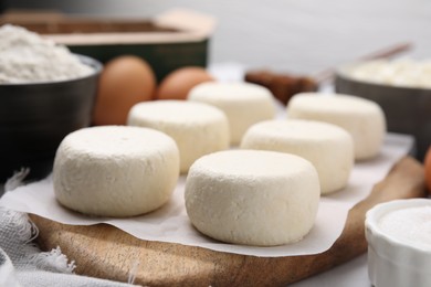 Photo of Uncooked cottage cheese pancakes and different ingredients on white table, closeup