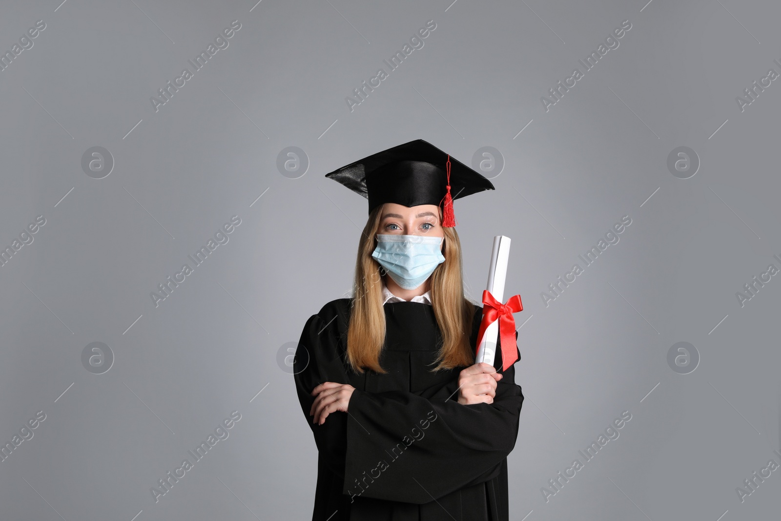 Photo of Student in protective mask with diploma on grey background