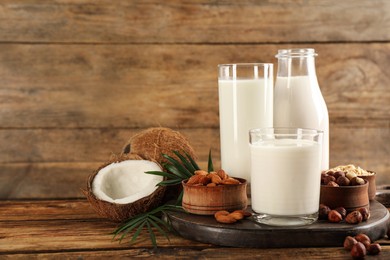 Photo of Different vegan milks and ingredients on wooden table. Space for text