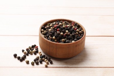 Photo of Aromatic spices. Different peppers in bowl on wooden table