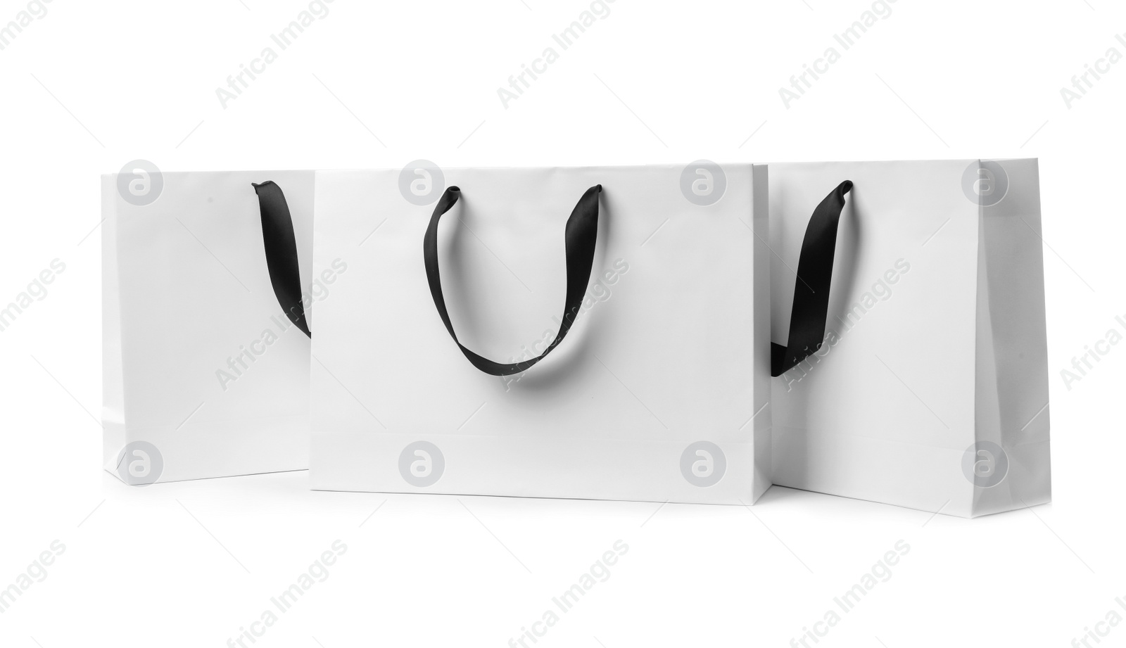 Photo of Paper shopping bags with ribbon handles on white background. Mockup for design