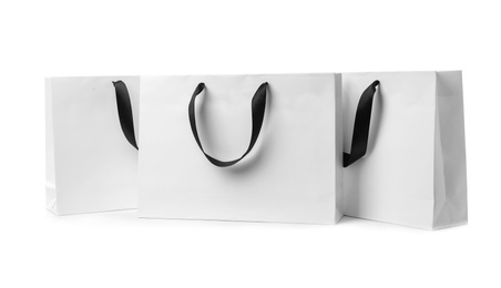 Photo of Paper shopping bags with ribbon handles on white background. Mockup for design