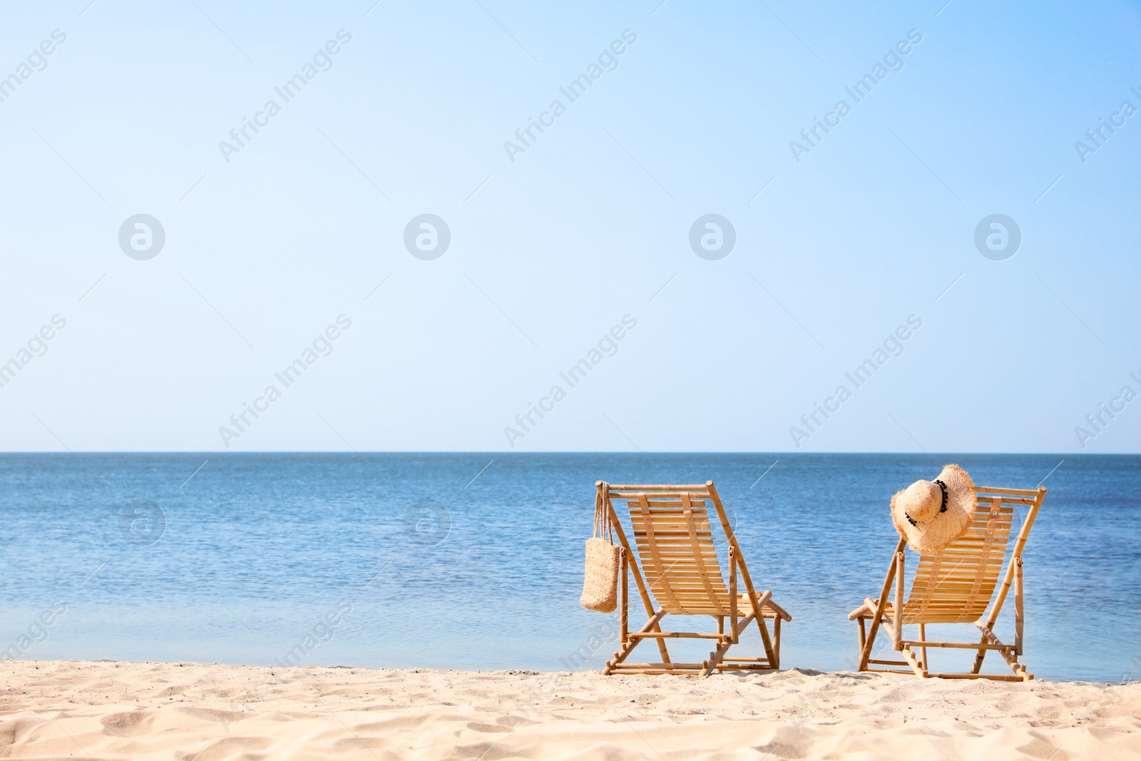 Photo of Wooden deck chairs on sandy beach near sea