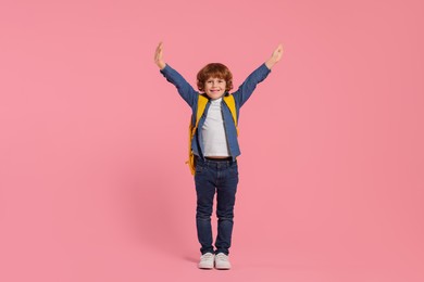 Photo of Happy schoolboy with backpack on pink background
