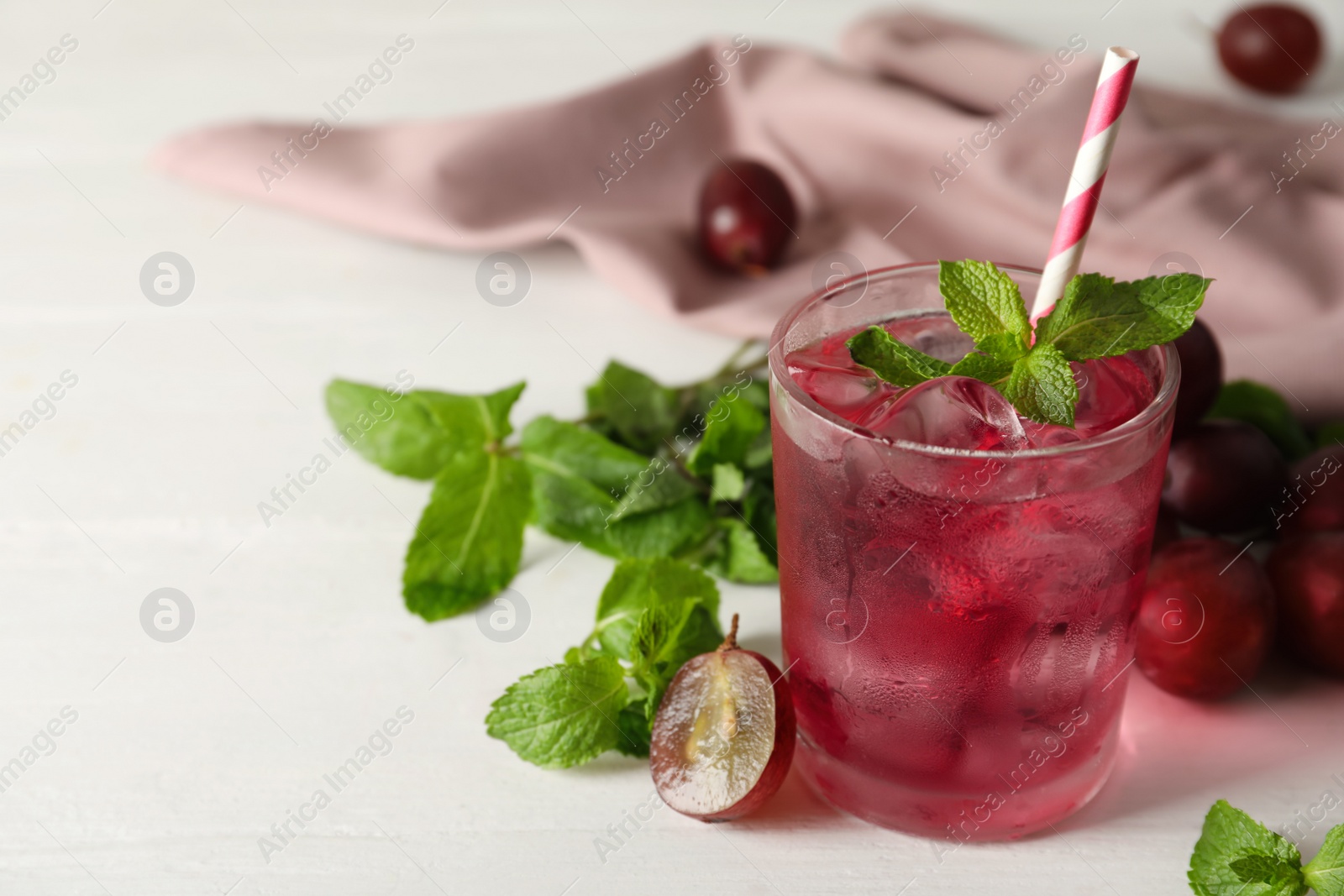 Photo of Delicious grape soda water with mint on white table. Refreshing drink