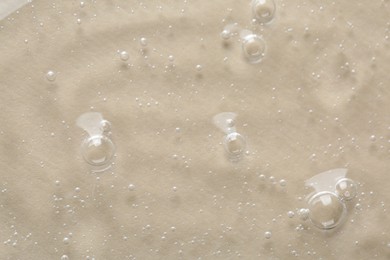 Clear cosmetic serum on beige background, macro view