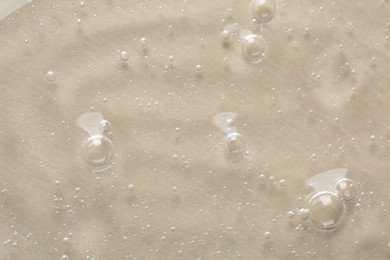 Photo of Clear cosmetic serum on beige background, macro view