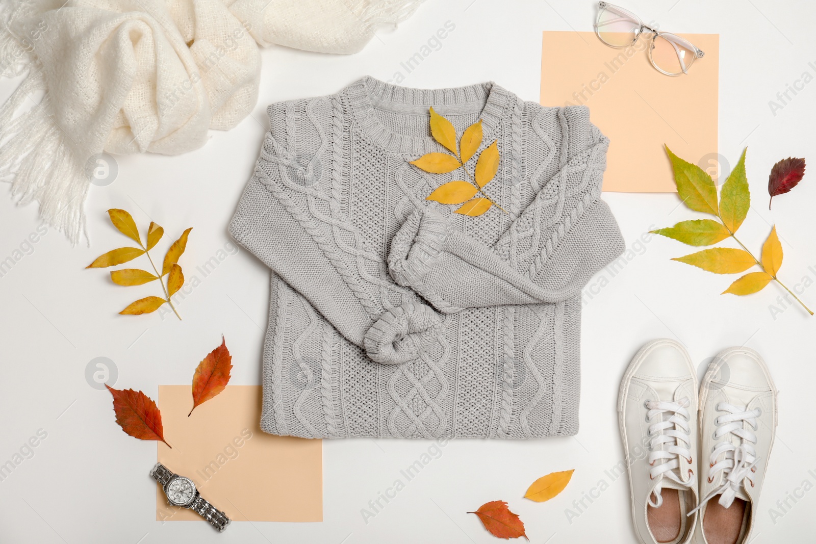 Photo of Stylish outfit and autumn leaves on white background, top view. Trendy warm clothes