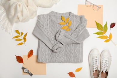 Photo of Stylish outfit and autumn leaves on white background, top view. Trendy warm clothes