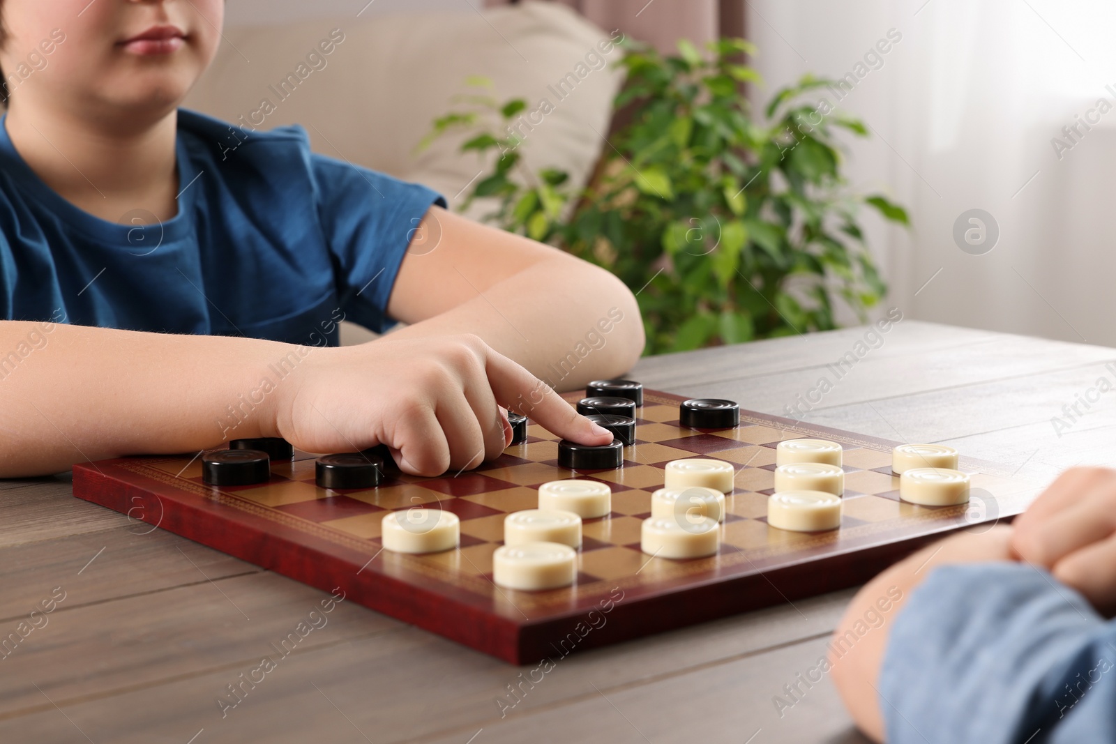 Photo of Children playing checkers at table in room, closeup