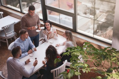 Group of coworkers having coffee break in cafe, above view