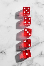 Many red game dices on white marble table, flat lay