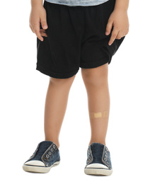 Photo of Little boy with sticking plaster on leg against white background, closeup