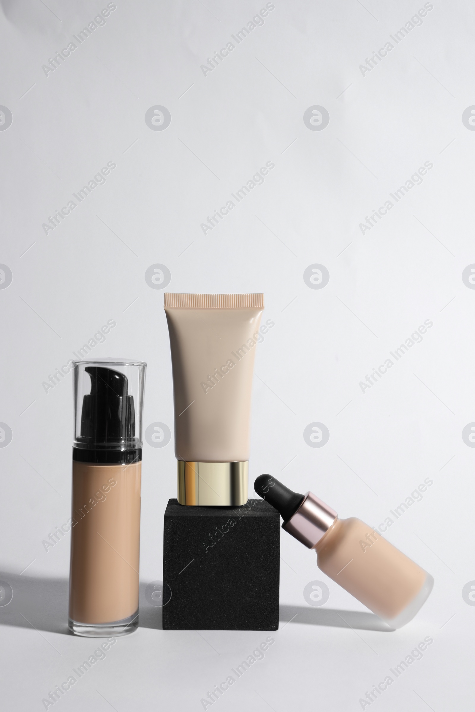 Photo of Bottles and tube of skin foundation on white background. Makeup product
