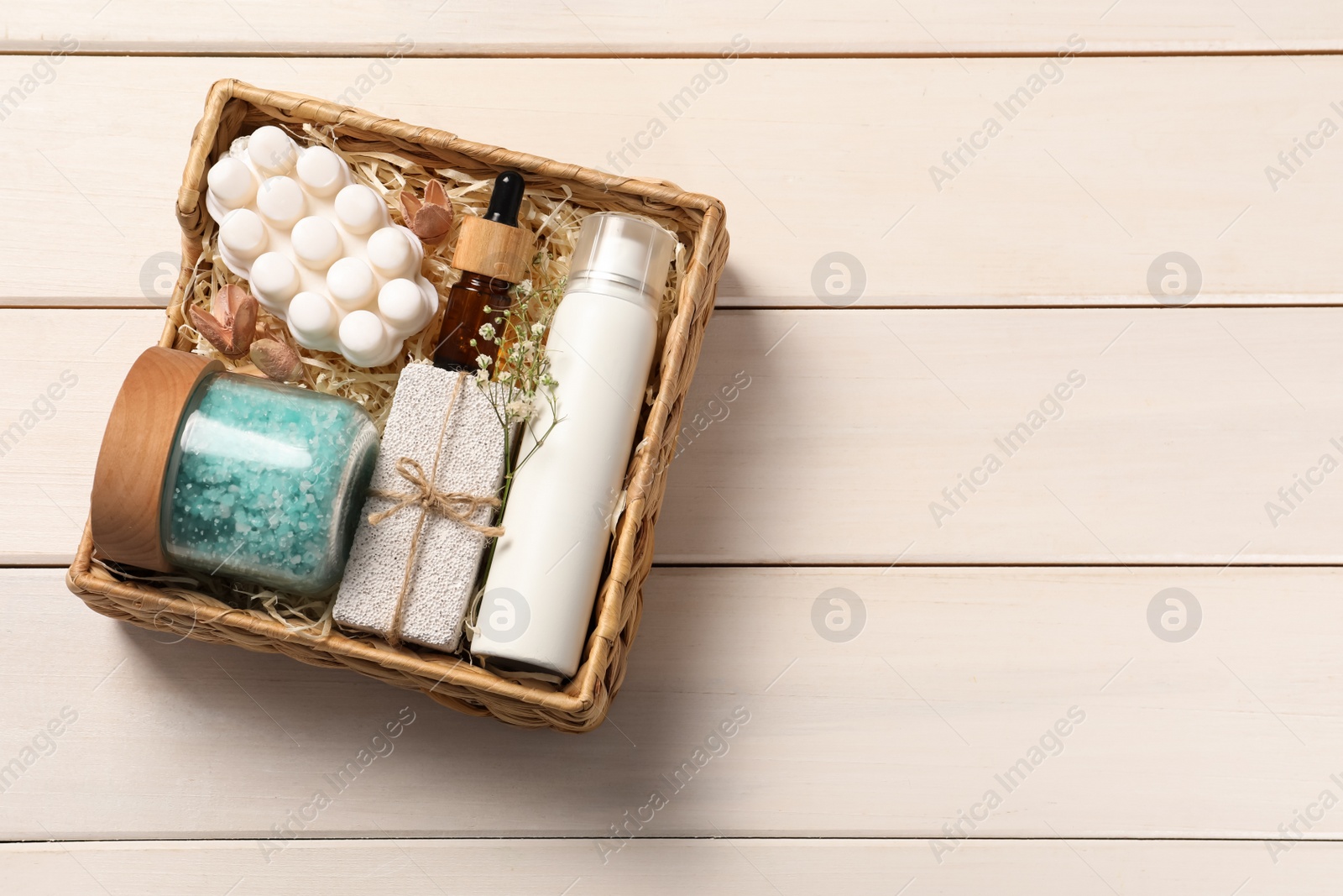 Photo of Spa gift set with different products in wicker box on white wooden table, top view. Space for text