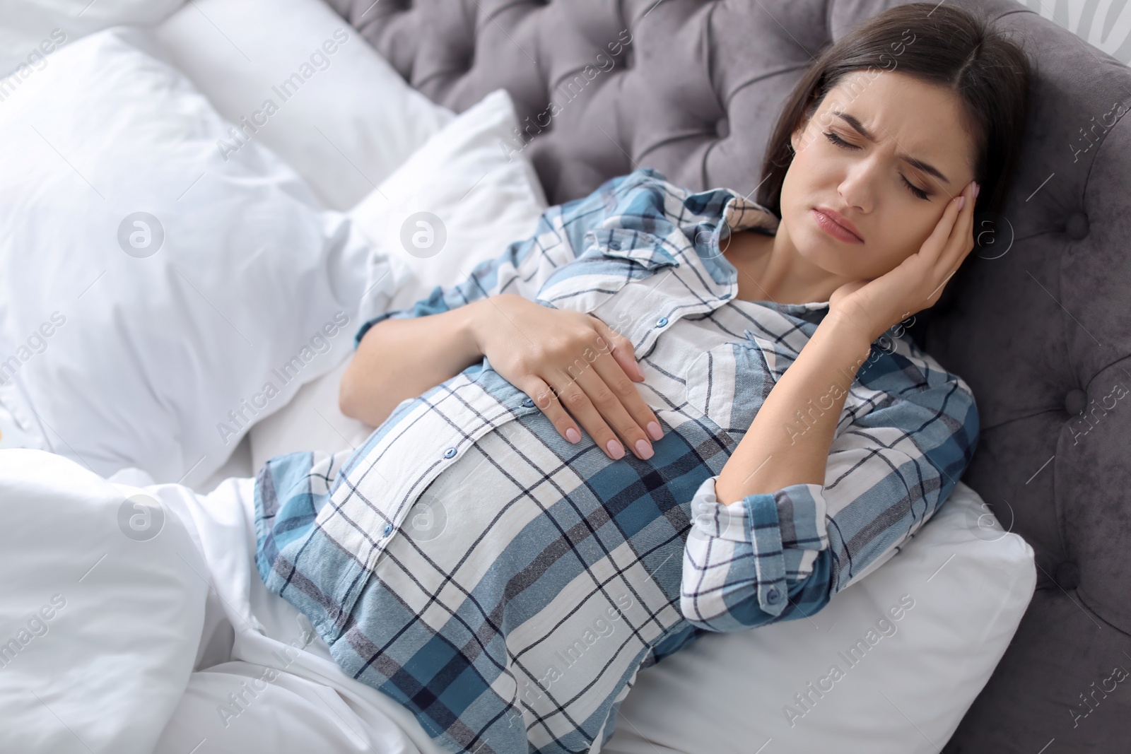 Photo of Young pregnant woman suffering from headache at home