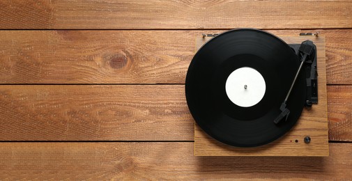 Photo of Turntable with vinyl record on wooden background, top view. Space for text