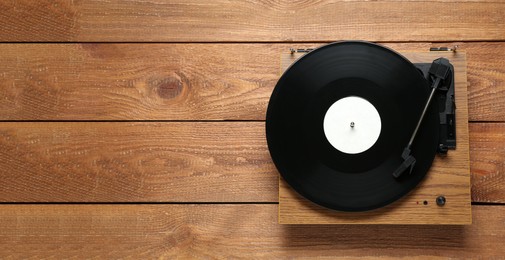 Turntable with vinyl record on wooden background, top view. Space for text