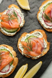 Photo of Tasty canapes with salmon, cucumber, radish and cream cheese on table, top view