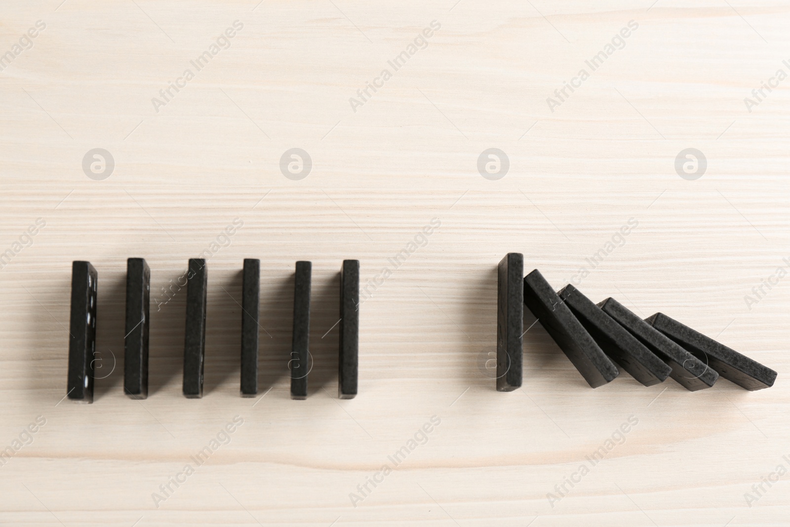 Photo of Black domino tiles on white wooden background, flat lay