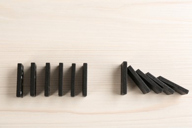 Black domino tiles on white wooden background, flat lay