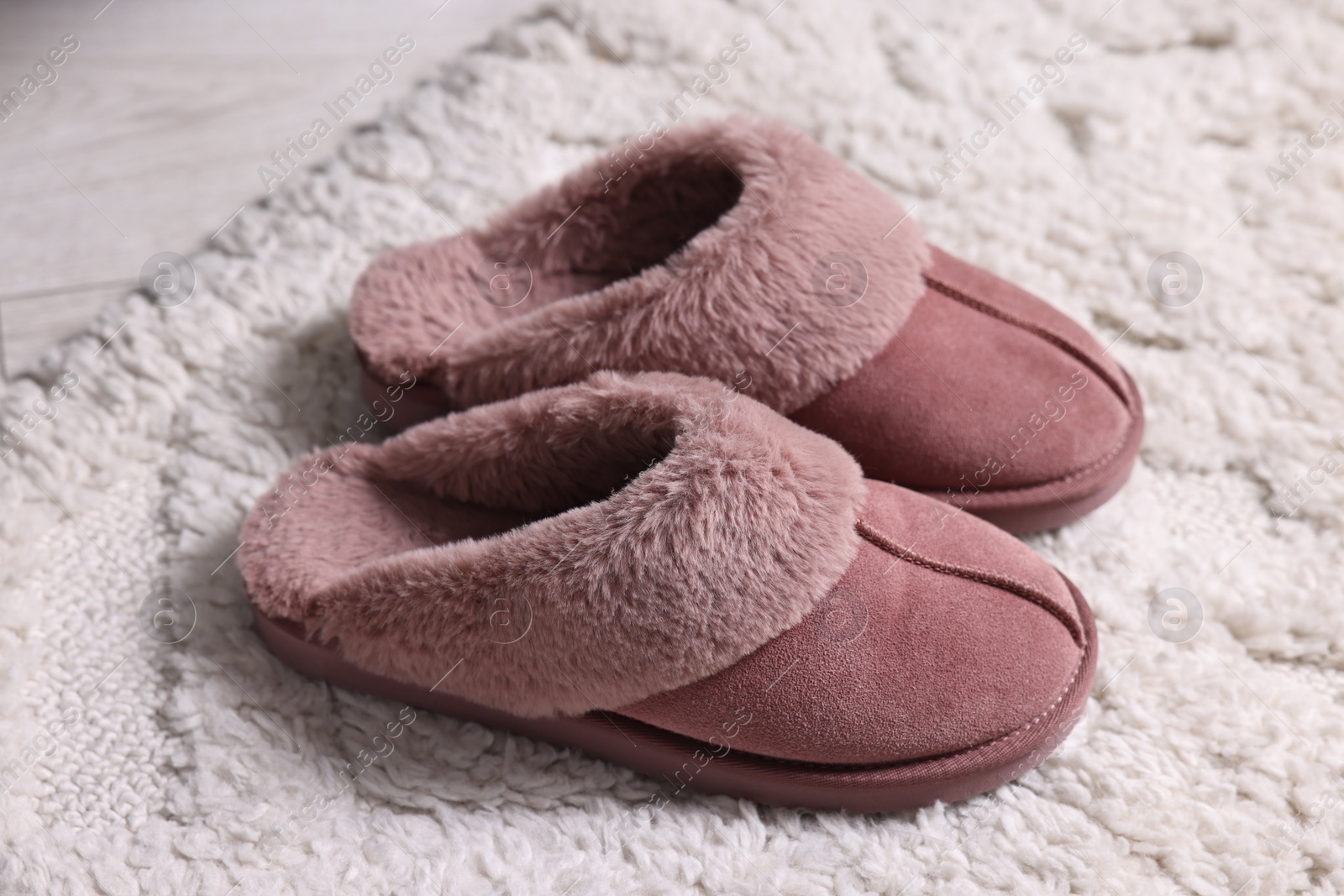 Photo of Pink soft slippers on carpet indoors, closeup