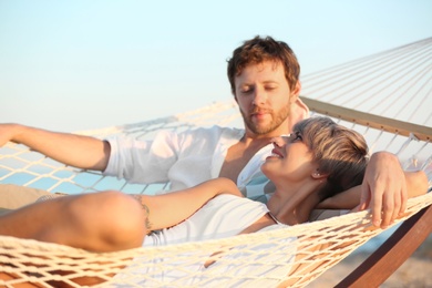 Photo of Young couple resting in hammock on beach