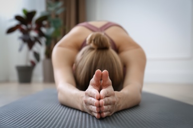 Photo of Young woman practicing extended child asana in yoga studio, focus on hands. Utthita Balasana pose