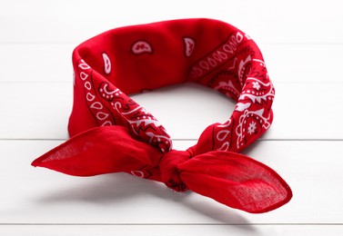 Photo of Tied red bandana with paisley pattern on white wooden table