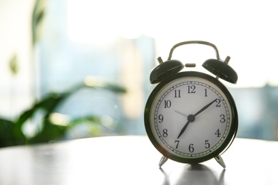 Photo of Black alarm clock on table in morning. Space for text