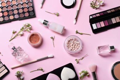 Flat lay composition with different makeup products and beautiful spring flowers on pink background