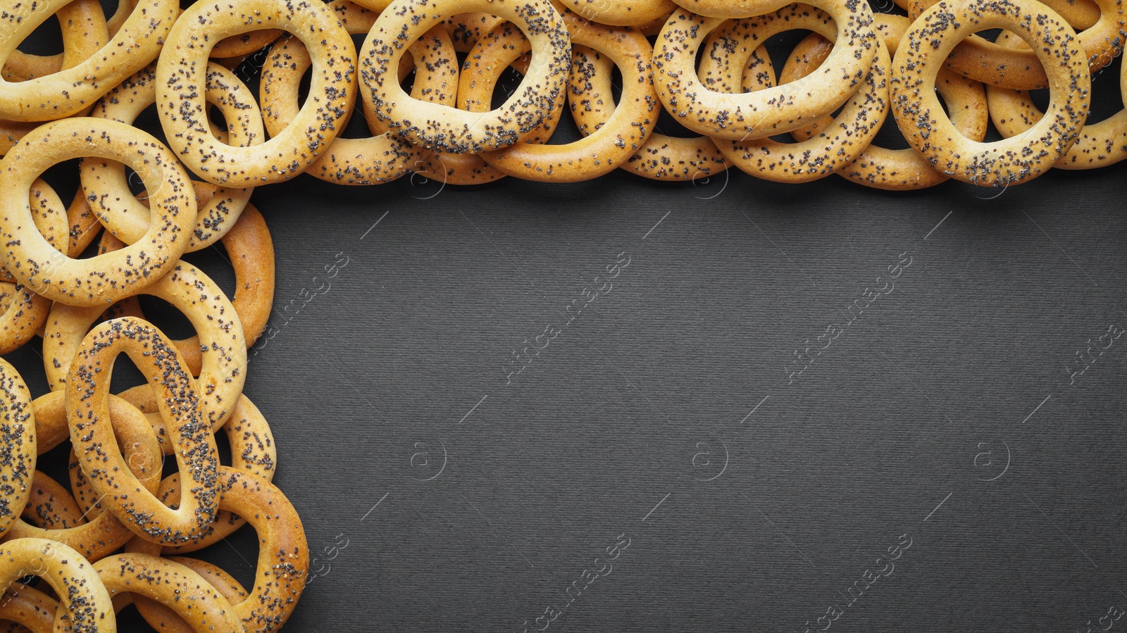 Photo of Many delicious ring shaped Sushki (dry bagels) on dark blue background, flat lay. Space for text