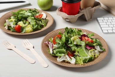 Plates of fresh salad and cutlery on white wooden table. Business lunch