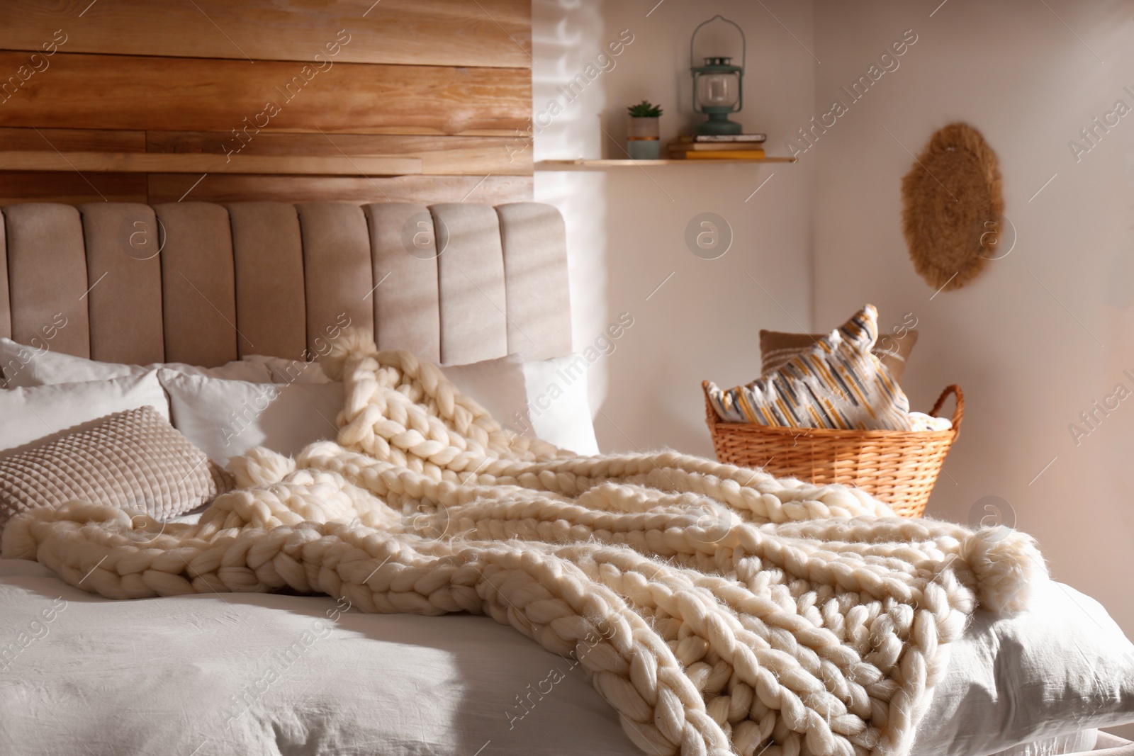 Photo of Bed with white knitted plaid in room. Interior design