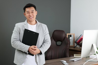 Photo of Happy boss holding clipboard in his modern office