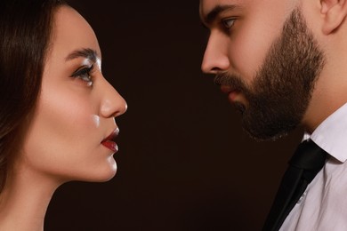 Photo of Handsome bearded man and sexy lady on dark brown background, closeup