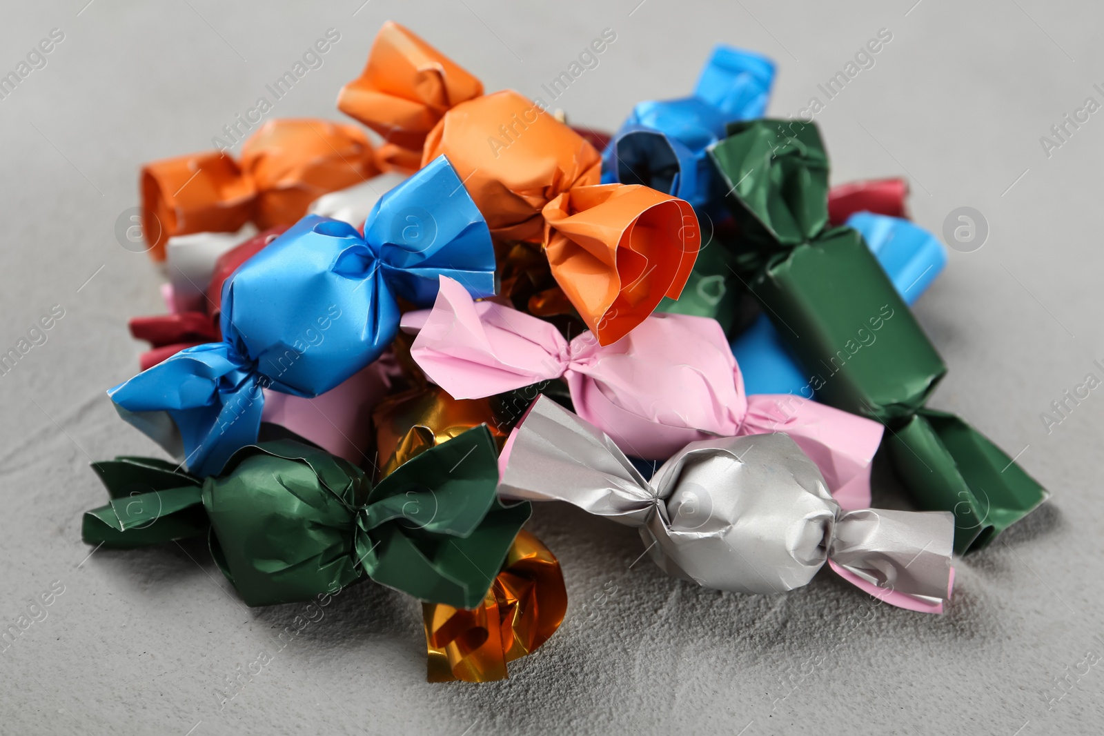 Photo of Candies in colorful wrappers on grey table