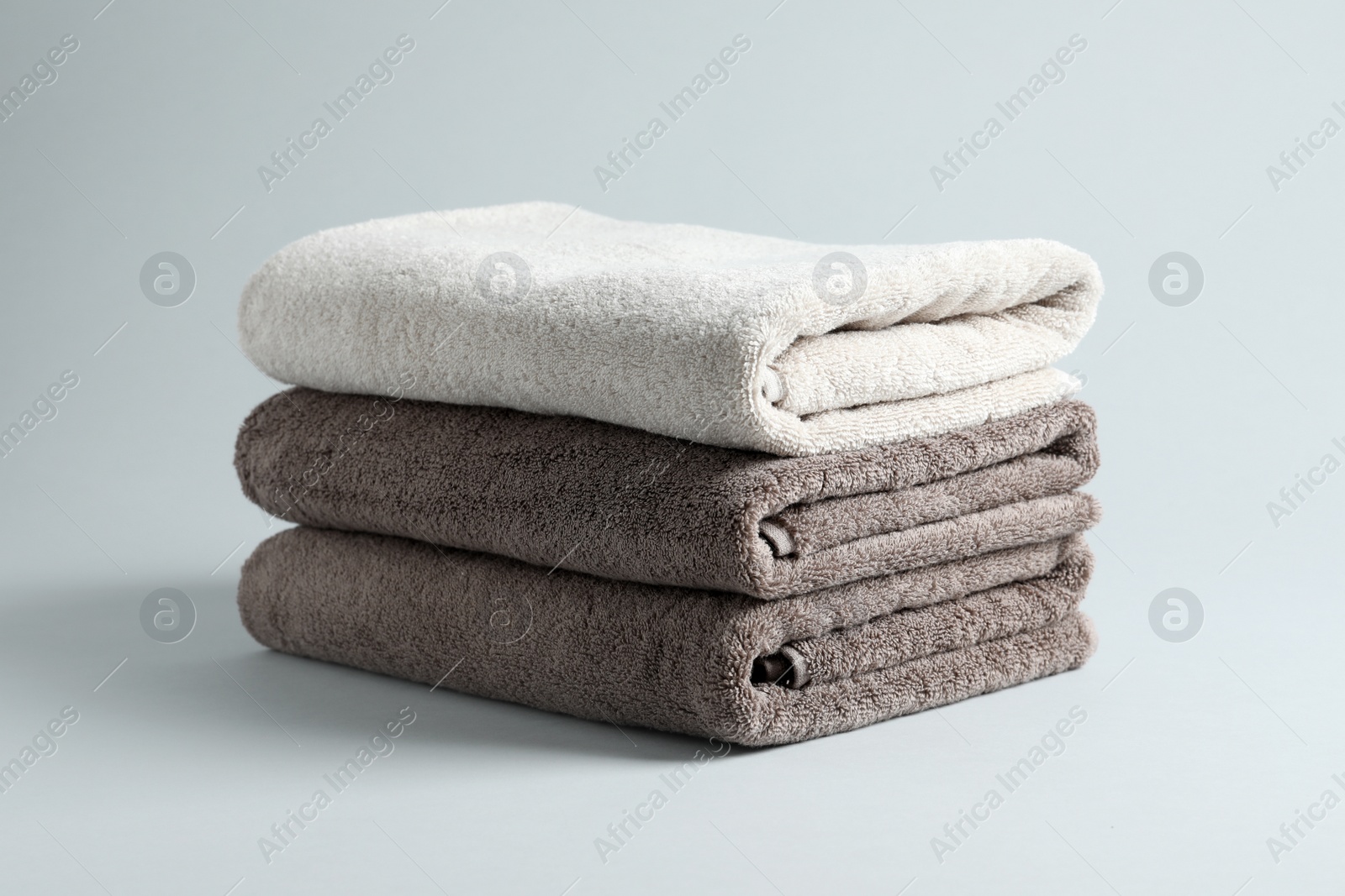 Photo of Stack of fresh fluffy towels on grey background